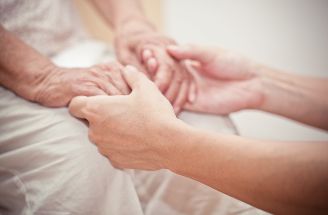 Pflegekraft hält Hand von Patienten