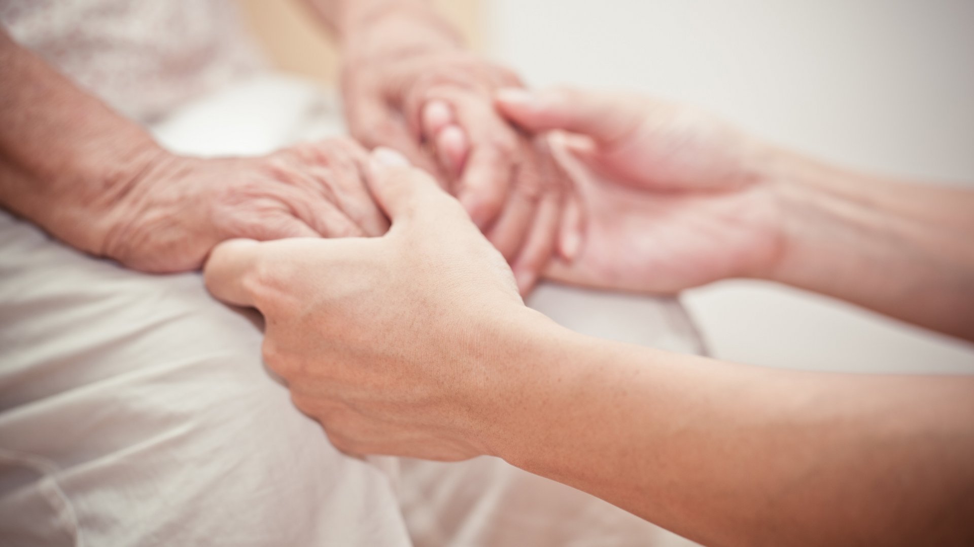 Pflege hält Hand von Patienten